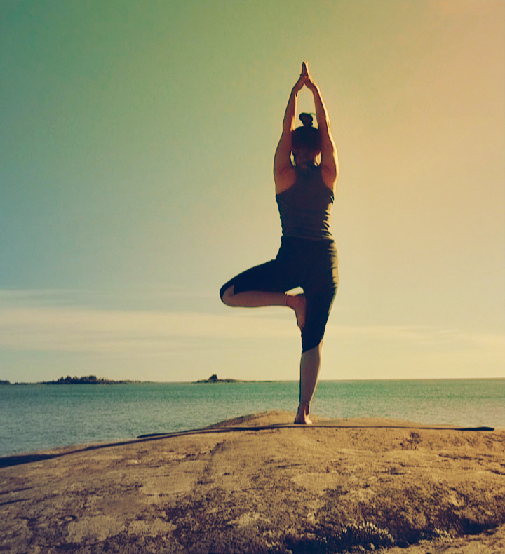 Woman does yoga on the cliffs